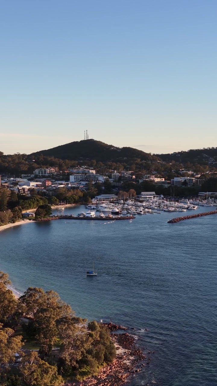 Højvinkel droneoptagelse af både fortøjet i Nelson Bay havn under den gyldne time, Australien