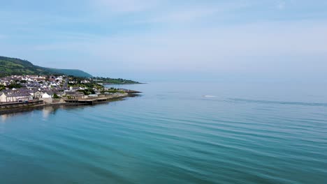 Rising-aerial-view-of-boat-moving-towards-North-Coast-town-in-Northern-Ireland