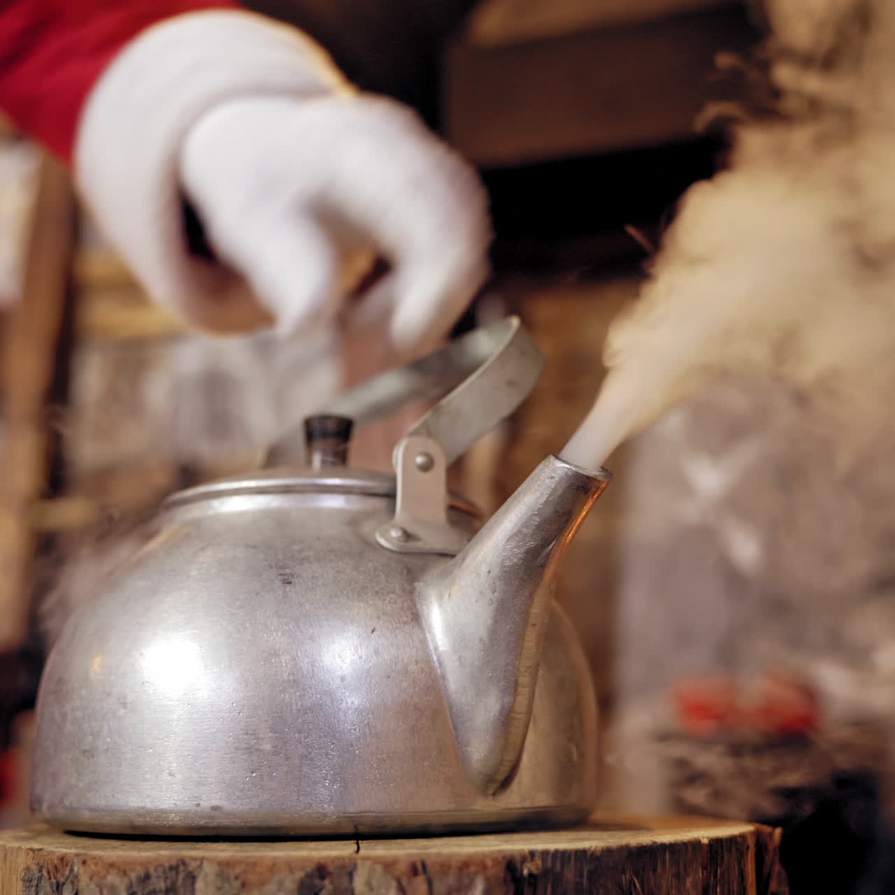 Metal kettle boiling with white steam. Santa removing the cover of the kettle with hot water indoors. Close-up. Christmas time.