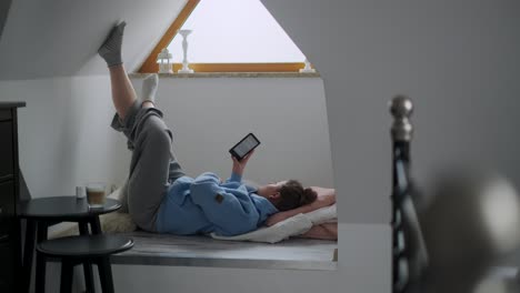 woman relaxing in attic with e-reader