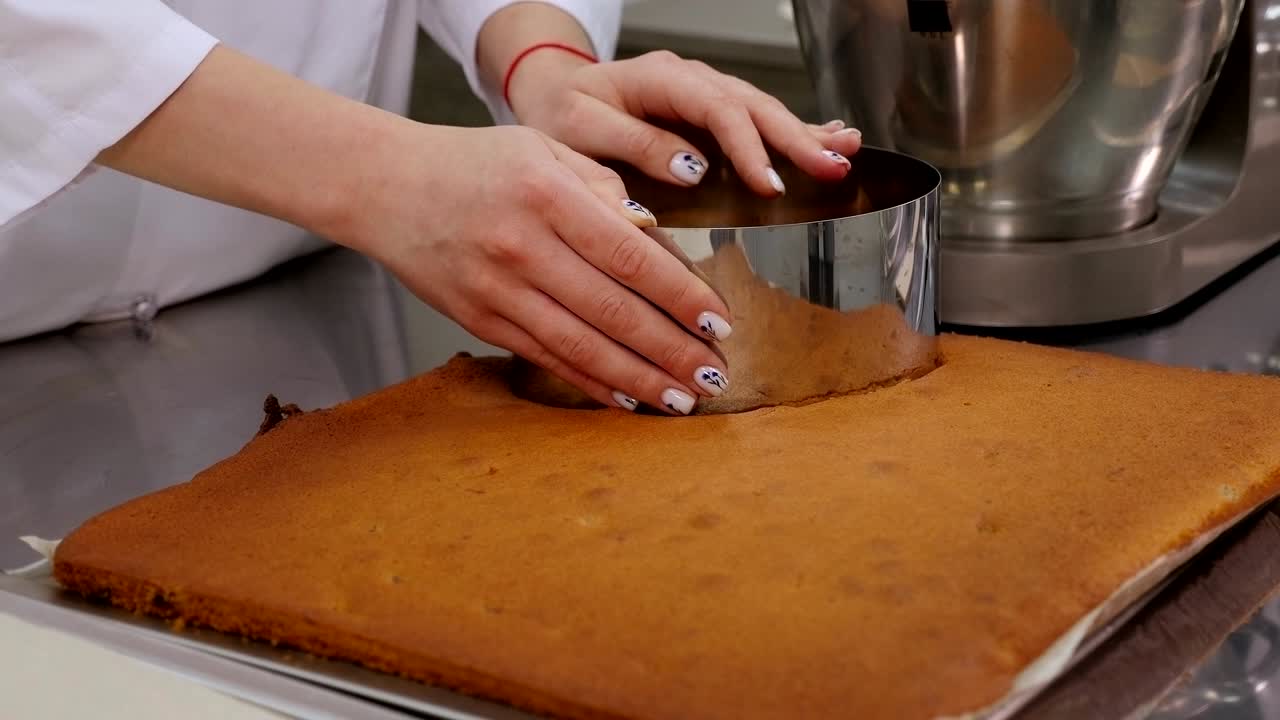 페이스트리 셰프가 케이크를 위해 비스 반죽에서 둥근 모양을 잘라내는 클로즈업입니다.