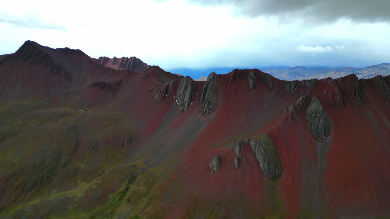 Cinematic 4K aerial of Peru’s red ridges during a storm. Curtains of mist and rain roll over the Andes, softening the rugged terrain into painterly tones
