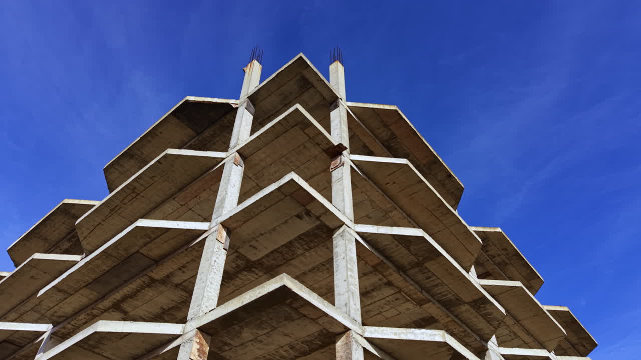 Struttura edilizia che si erge verso il cielo blu e limpido con travi in cemento ed elementi non finiti che mettono in mostra l'architettura moderna