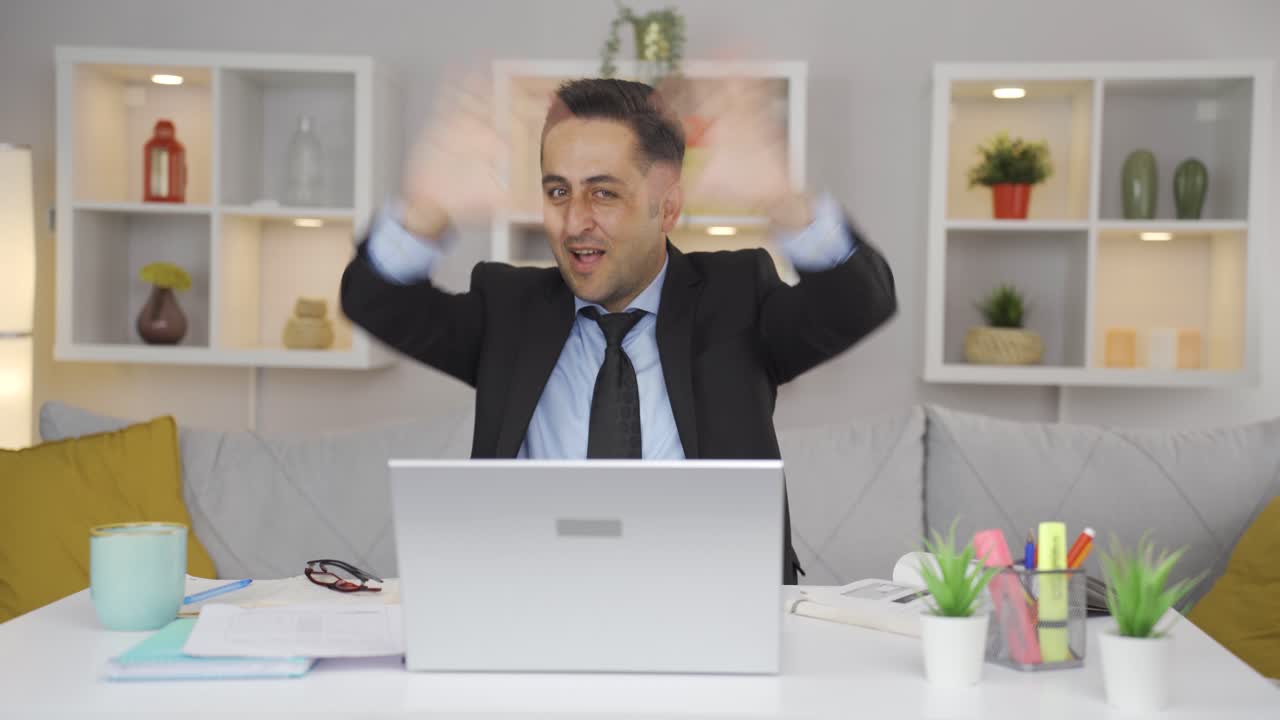 Home office worker man makes heart symbol looking at camera.