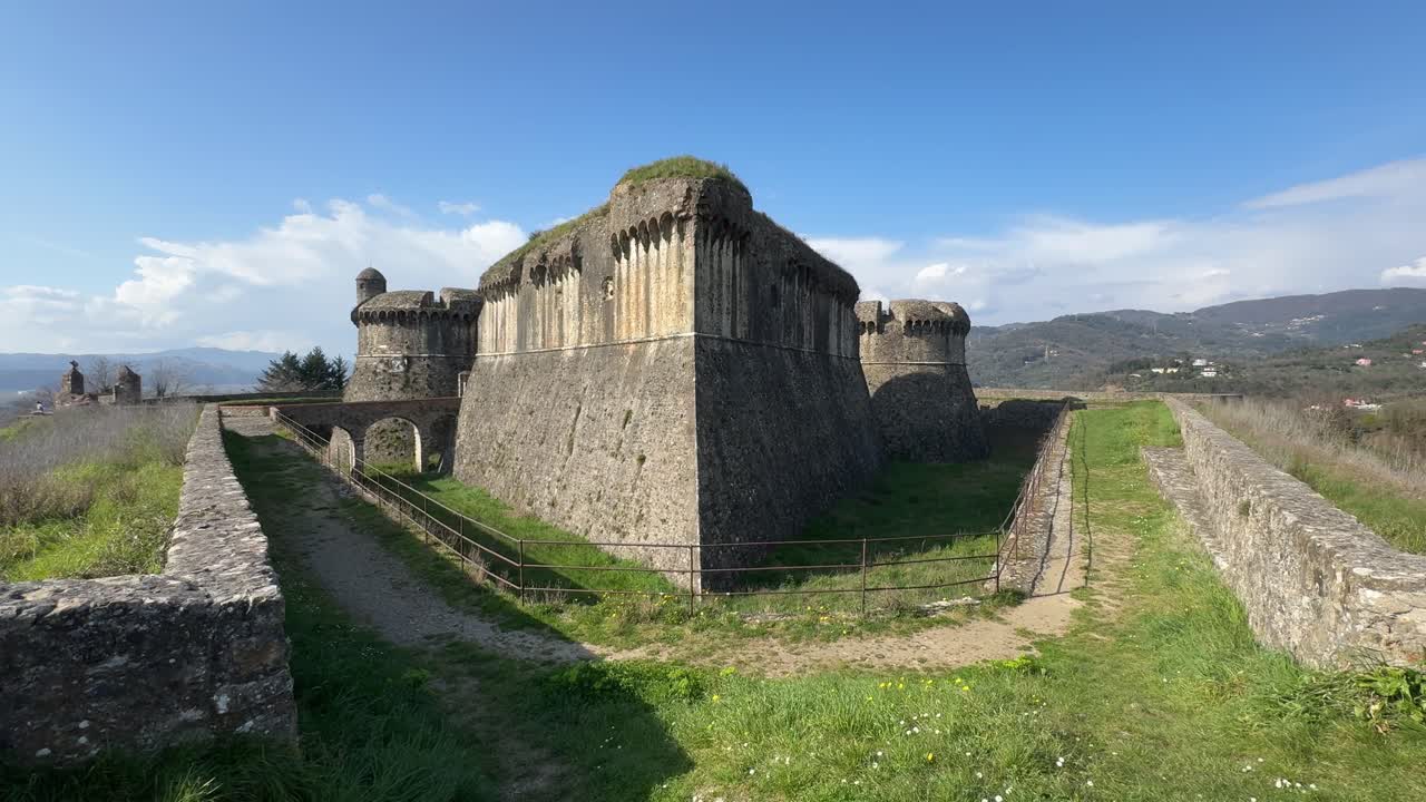 Sarzana, Liguria, İtalya'daki Sarzanello Kalesi'nin geniş görünümü, devasa taş kaleyi, hendeği ve çevredeki kırsal alanı içeriyor.