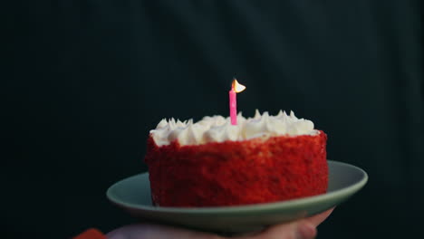 closeup hand holding birthday cake burning candle. festive party celebration