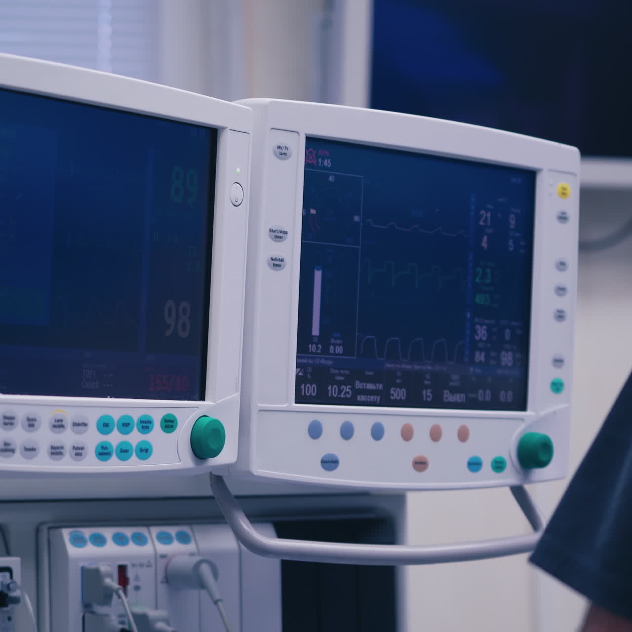 Hi-tech medical equipment. Two screens display of vital signs and cardiogram in modern clinic. Doctor is standing near monitors.