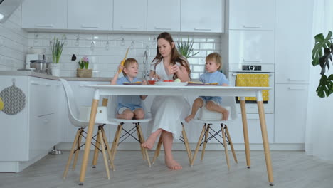 Beautiful-young-mother-with-two-children-sons-on-white-light-kuna-cook-with-burgers