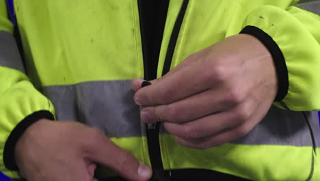 Male-wood-worker-prepares-for-his-shift-at-a-wood-mass-facility-by-putting-on-his-reflective-jacket-locker-room-personal-protective-equipment-hazardous-work-environments-wood-processing-tree-cutting