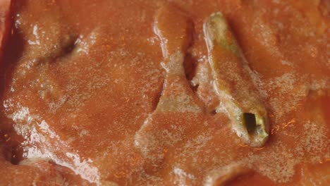 close-up of food with green vegetable in reddish-orange sauce
