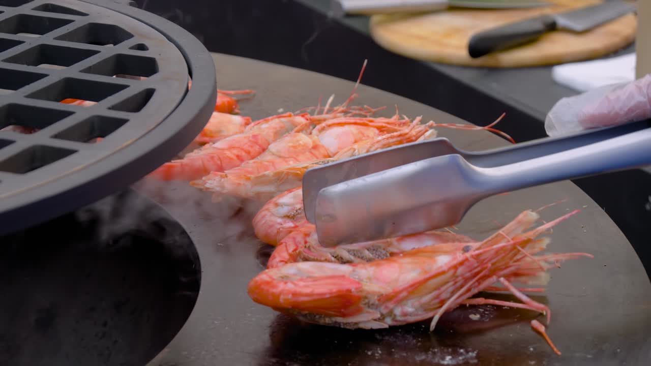 Slow motion: chef grilling fresh red king prawns on brazier - close up view