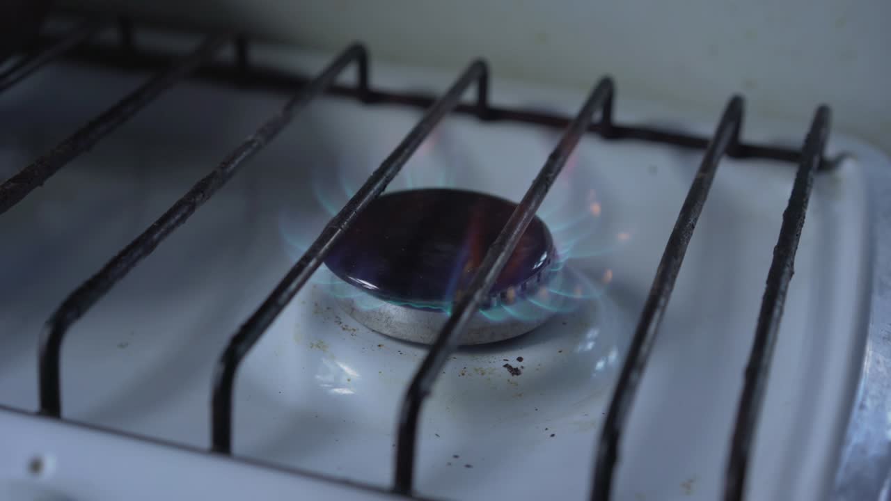 Blue gas burns on small black hob on stove in old house