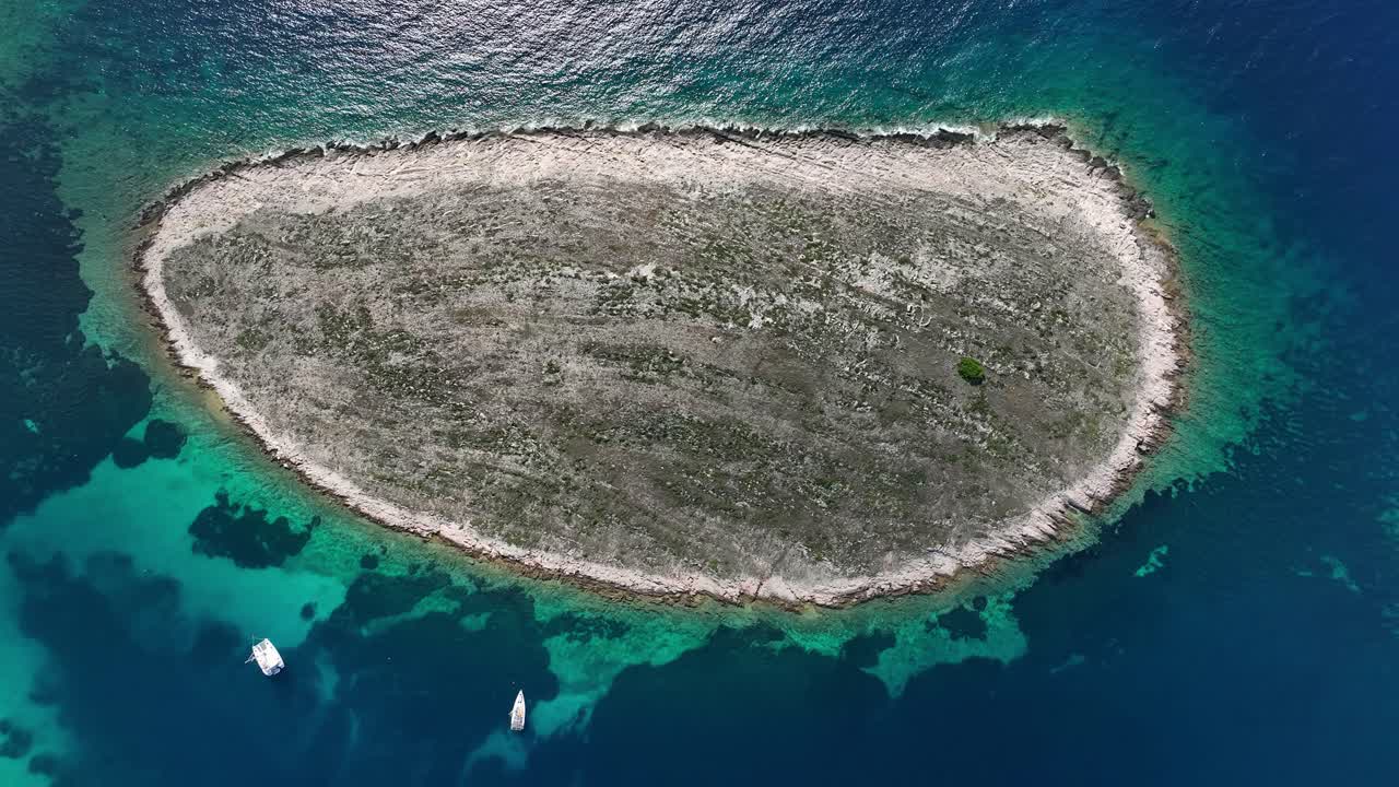 Rocky island surrounded by clear blue waters with boats near the shore in Kornati