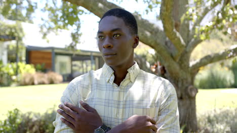 smiling african american man standing outdoors with arms crossed, enjoying sunny day in park