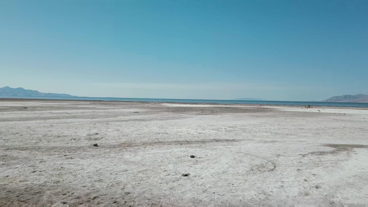 Dolly down a grassy path through shrubbery to sandy Black Rock state park