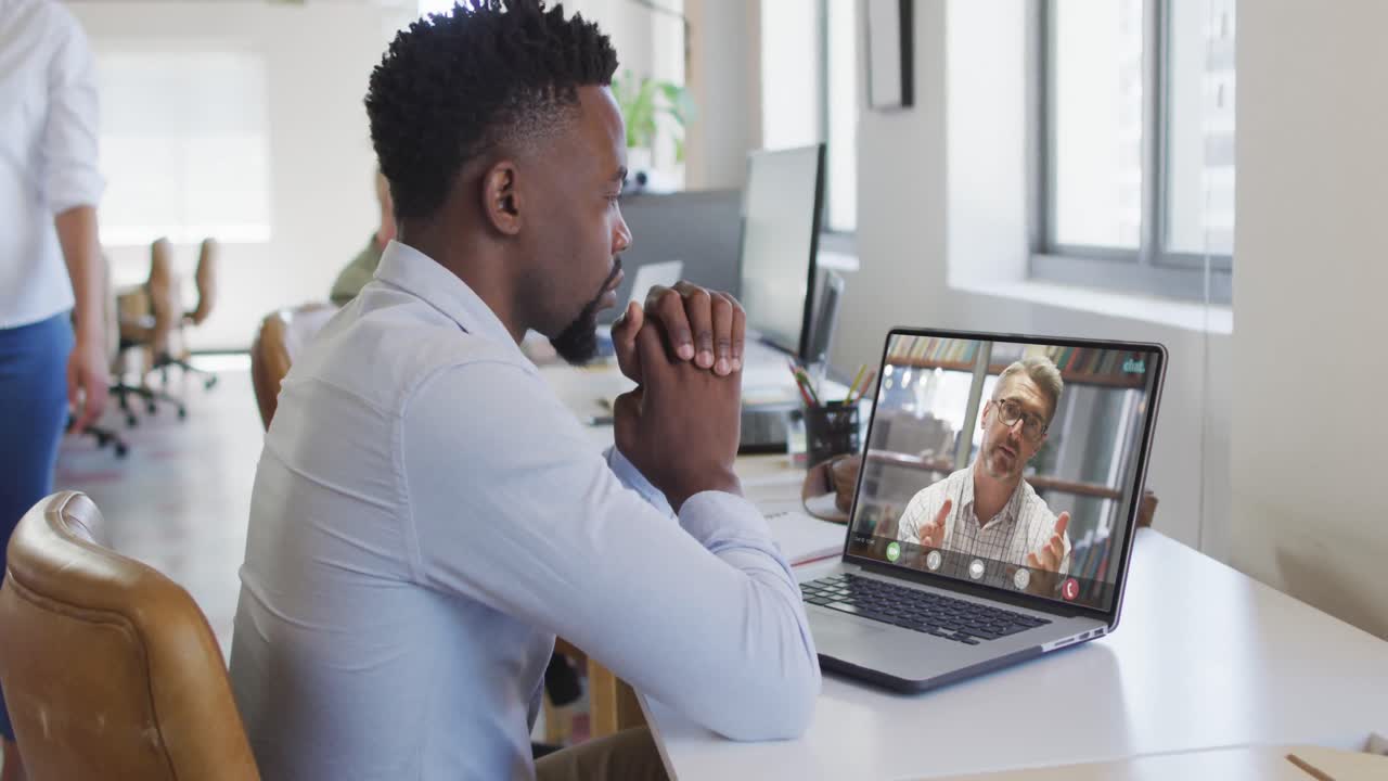 African american businessman using laptop for video call with caucasian business colleague