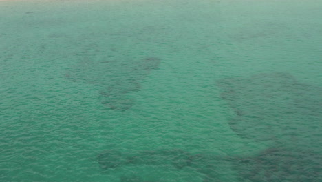 AERIAL:-Flight-over-beautiful-turquoise-blue-ocean-with-view-on-wilderness-in-Novalja,-Croatia-with-blue-sky-and-sun