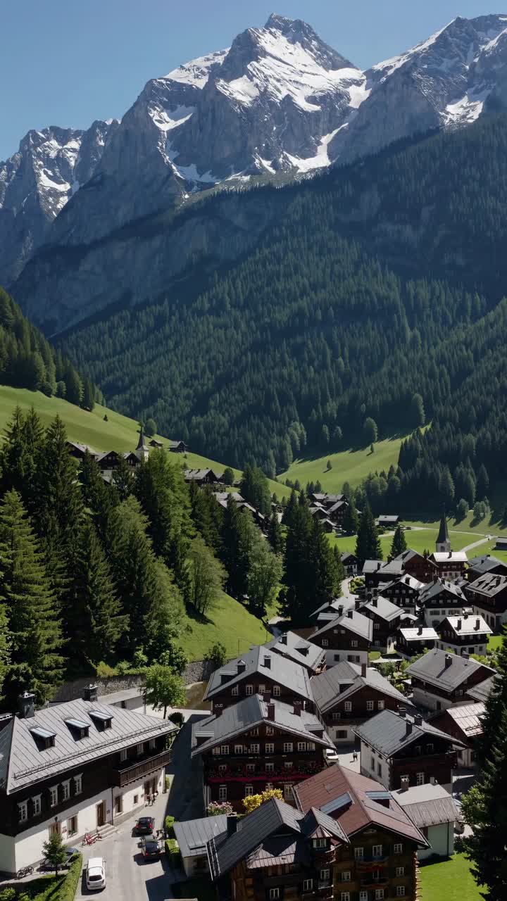 Aerial view of a picturesque alpine village nestled in lush green valleys with majestic snow-capped