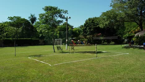 flying low over recreational green space,sports court surrounded with trees