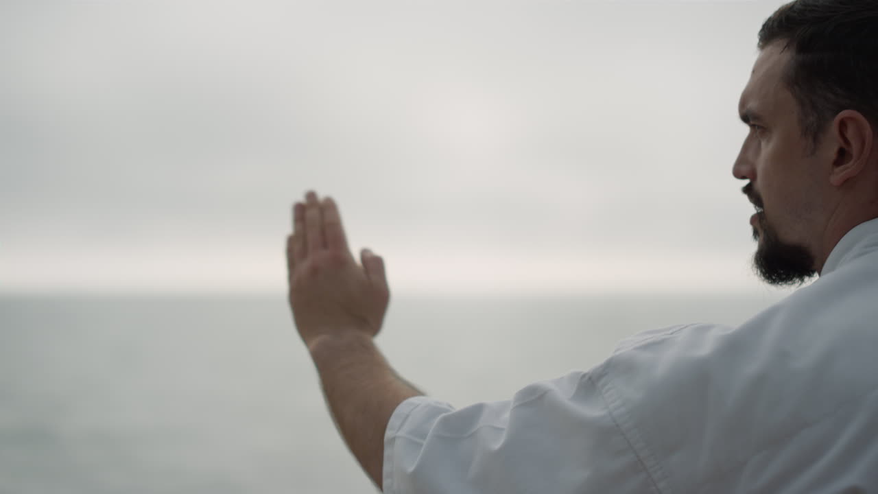 카라테 파이터가 해변에서 무술 기술을 훈련하고, 남자는  ⁇ 치를 연습합니다.