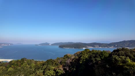 Scenic view of Amanohashidate Sandbar, a three kilometer isthmus, gracefully stretching across Miyazu Bay, framed by lush greenery and a vibrant blue sky