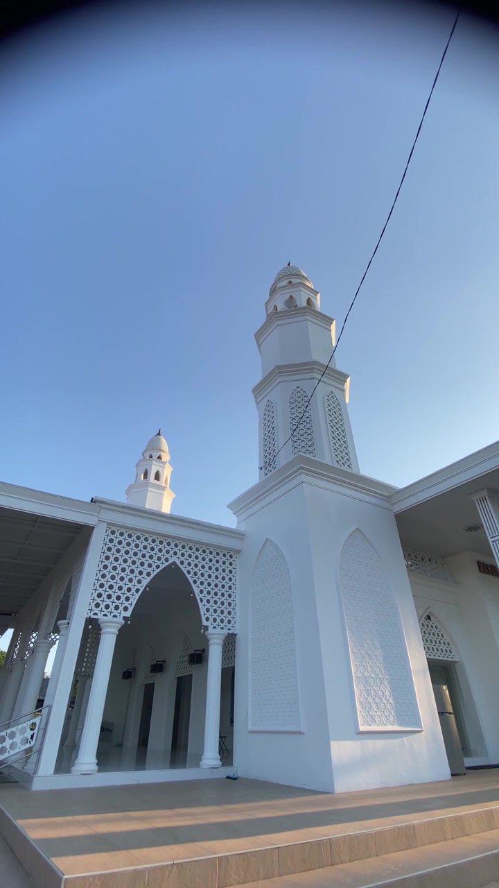 Moschea bianca moderna con minareti sotto un cielo azzurro e limpido