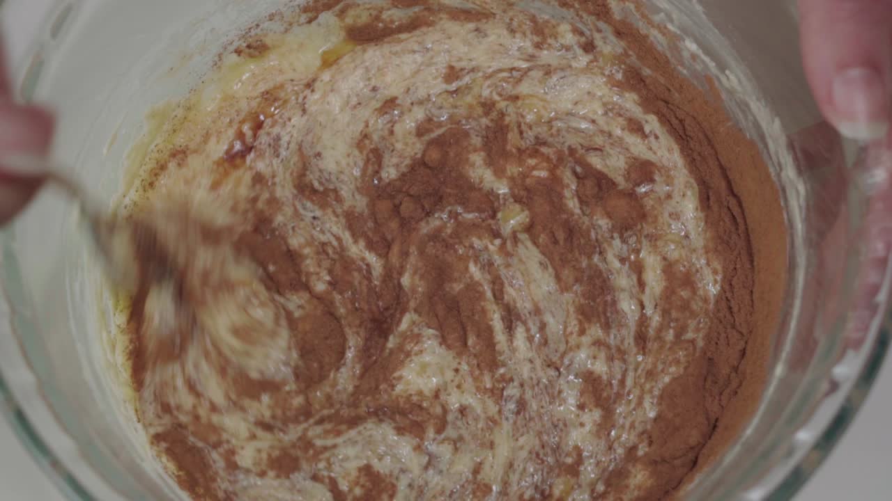 Mescolare cannella ed estratto di vaniglia nella pastella gialla, primo piano dall'alto.