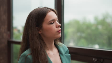 retrato de una mujer joven en una chaqueta verde mirando hacia abajo