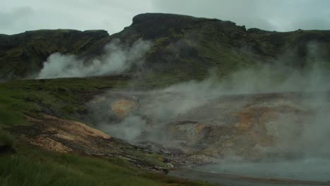 Isländische-Landschaft,-Geothermischer-Heißer-Dampfrauch-Steigt-Auf,-Entfernte-Figur-Eines-Fotografen,-Der-Ein-Bild-Einer-Ganzen-Szene-Macht,-Weitwinkelobjektivaufnahme,-Kameraschwenk-Von-Links-Nach-Rechts