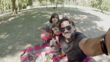 padre feliz tomando selfies con los niños en un picnic en un parque público