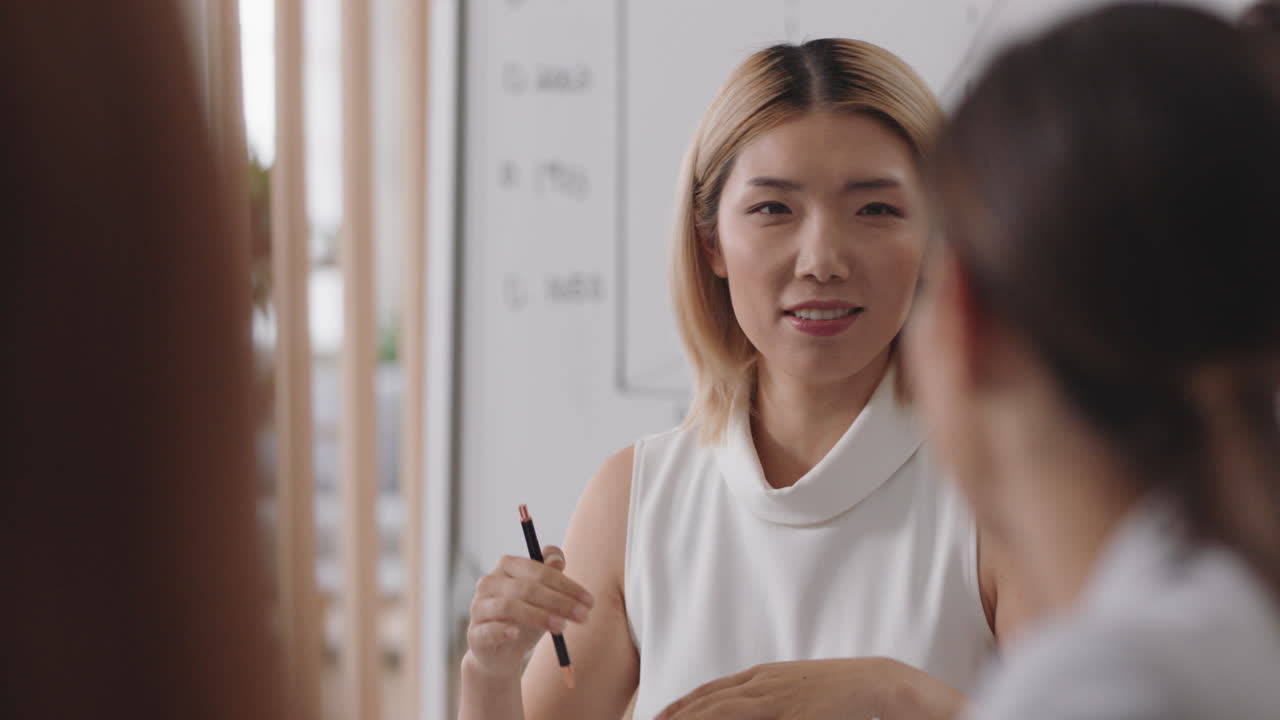 아시아의 사업가 팀 리더가 동료들과 만나 스타트업 프로젝트에 대한 창의적인 아이디어를 공유하고 사무실 이사회에서 기업 전략을 논의합니다.