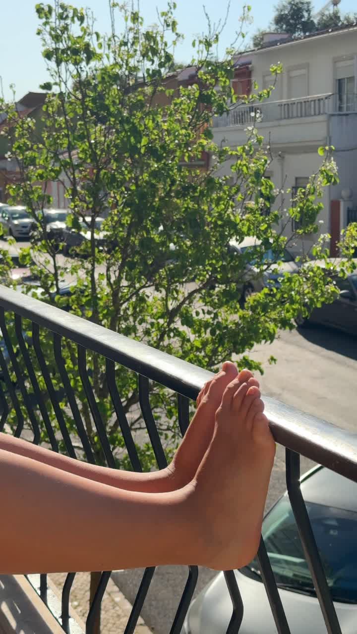 Feet resting on a balcony railing with a view