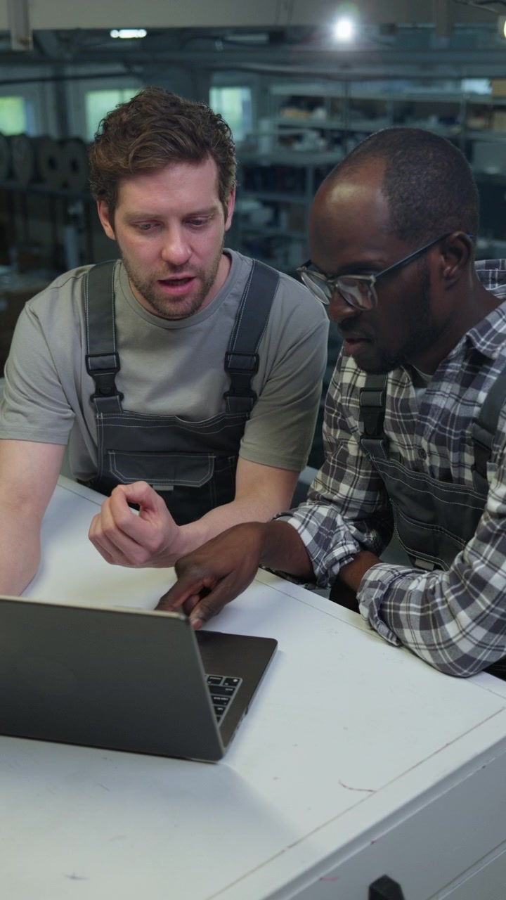 Two Diverse Factory Engineers Discussing Production Data on Laptop