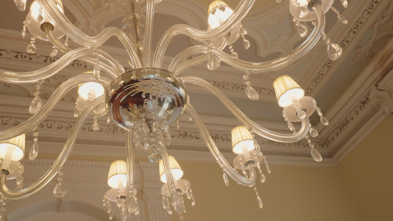 close up of ornate glass chandelier with crystal drops and warm glowing lights