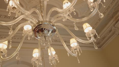 close up of ornate glass chandelier with crystal drops and warm glowing lights