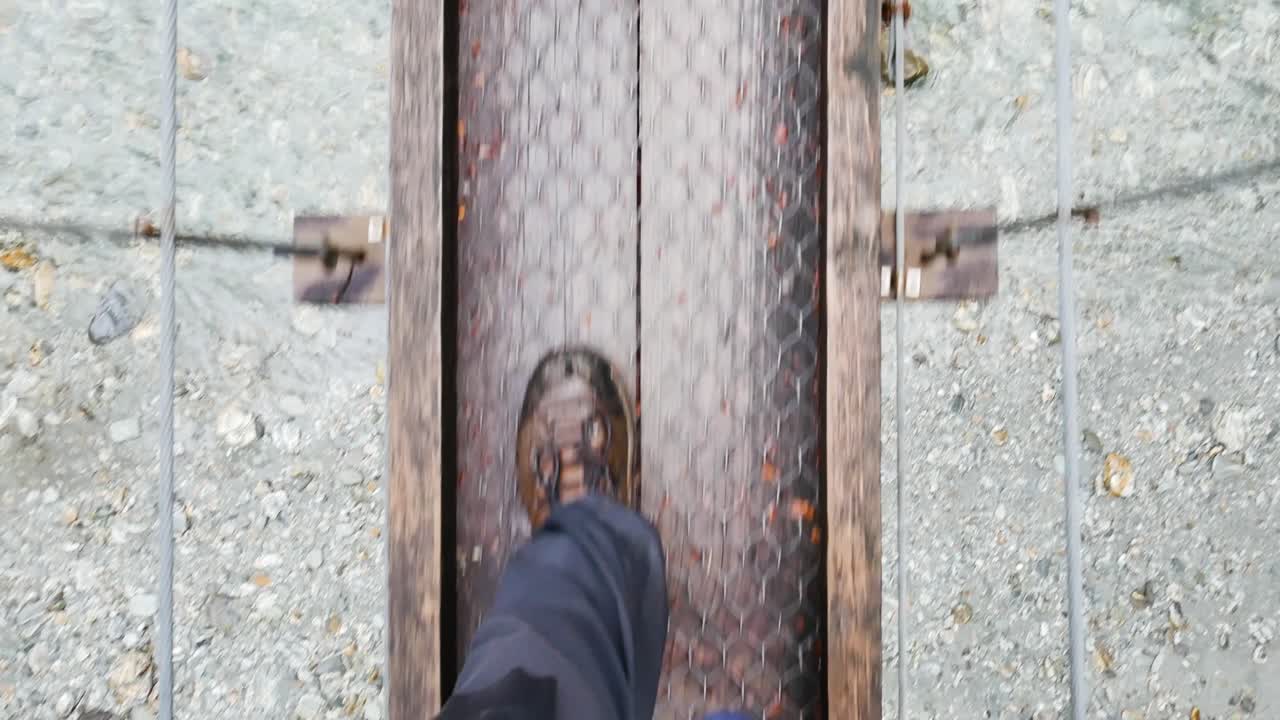 POV of hiker's wet boots as they cross a remote footbridge