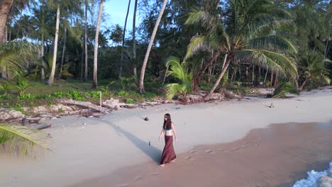 Mujer-Caminando-Con-Falda-Larga-A-Través-De-Las-Olas-En-La-Playa-Del-Paraíso-Natural