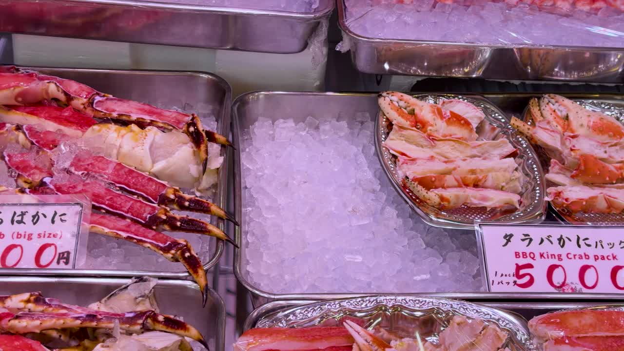 Close-up panning shot of king crab legs, oysters, and scallops on ice in Tokyo