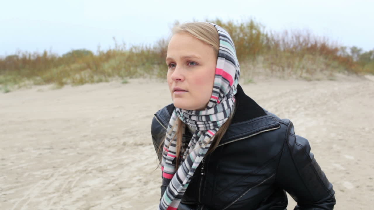 어린 소녀가 바다 근처의 벤치에 앉아 있습니다.