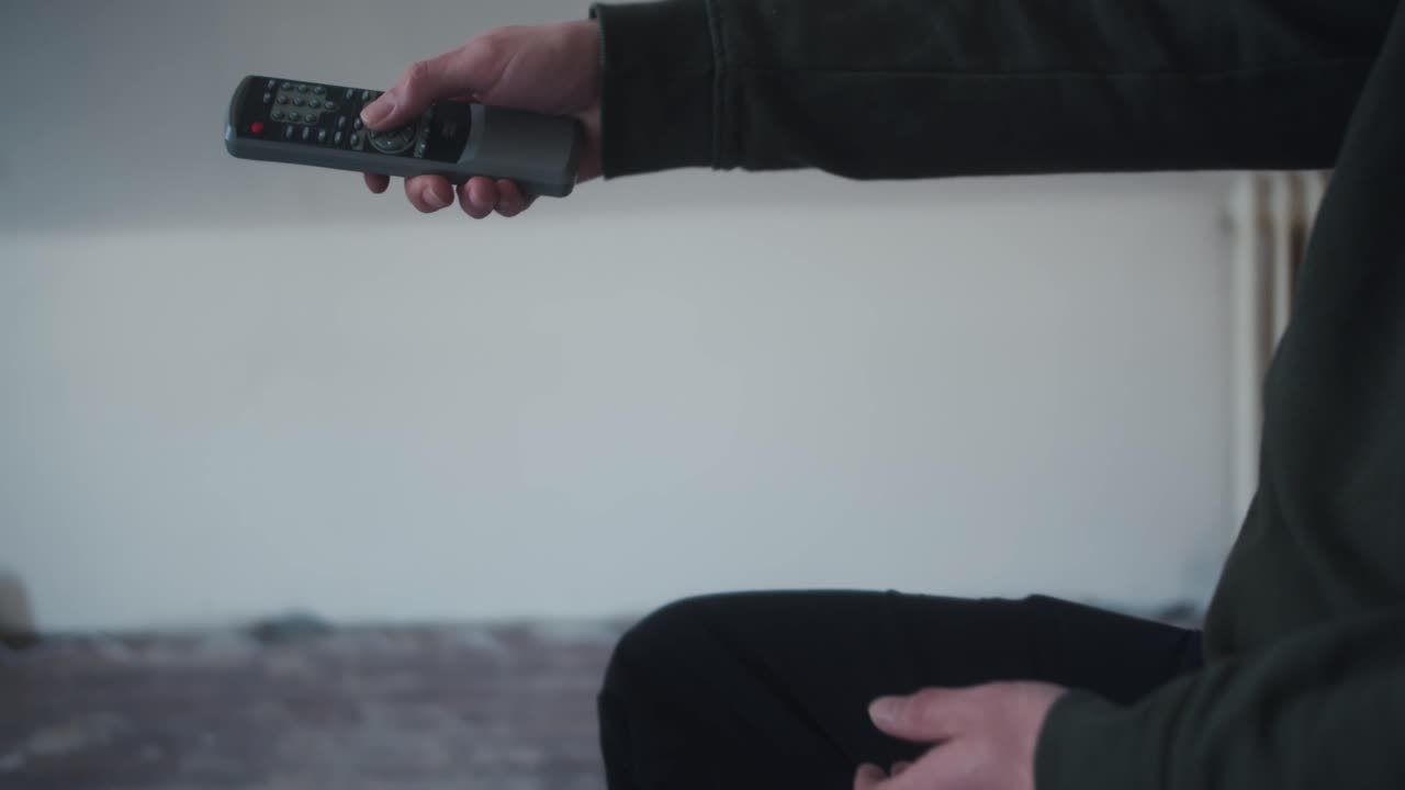 Man Sitting and Watching TV with a Remote Control