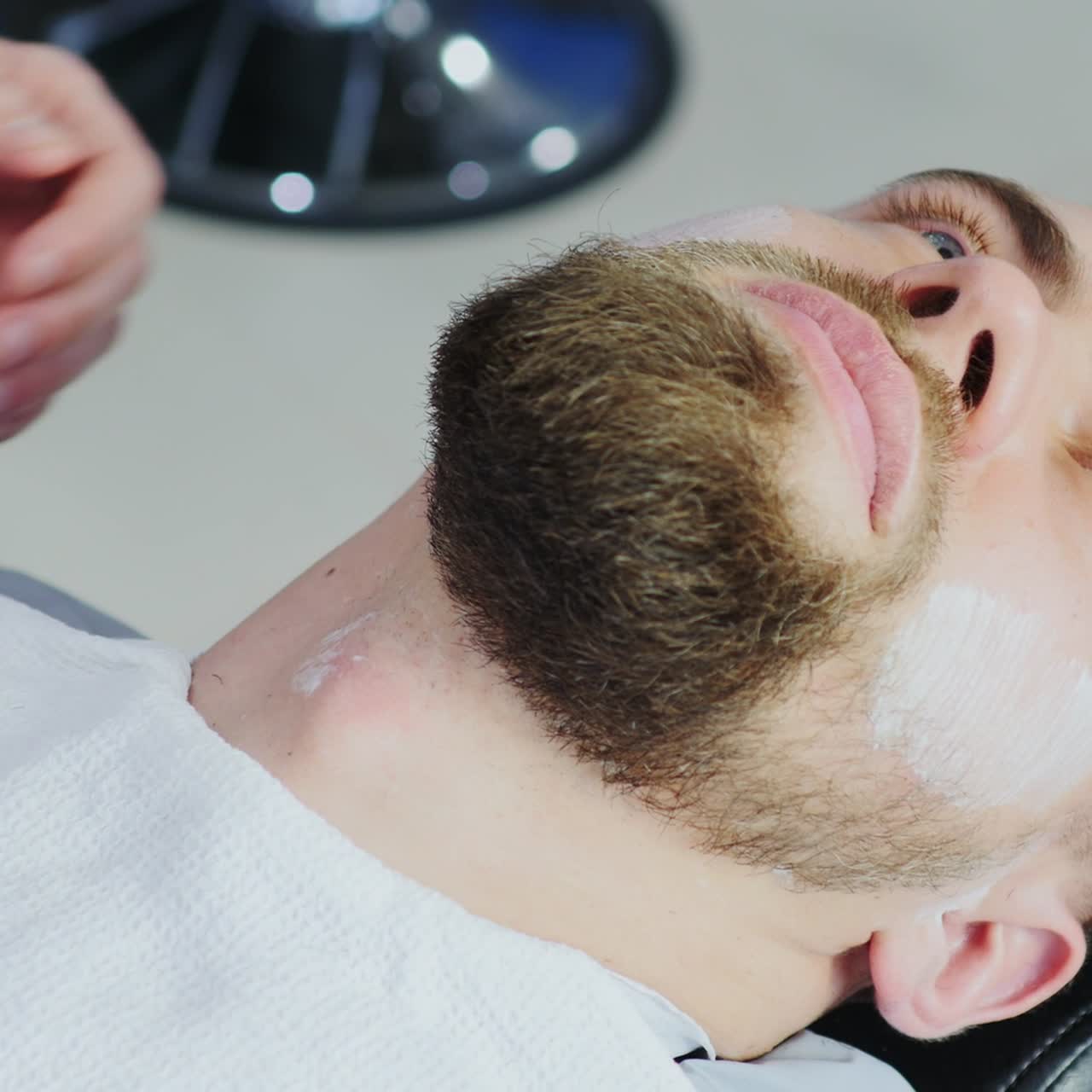 Frisør barberer kundens skæg med barberblad