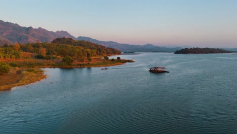 Drone-shot-of-a-the-mountains-on-a-lake-with-a-boat-and-a-shelter-in-the-center-of-the-lake