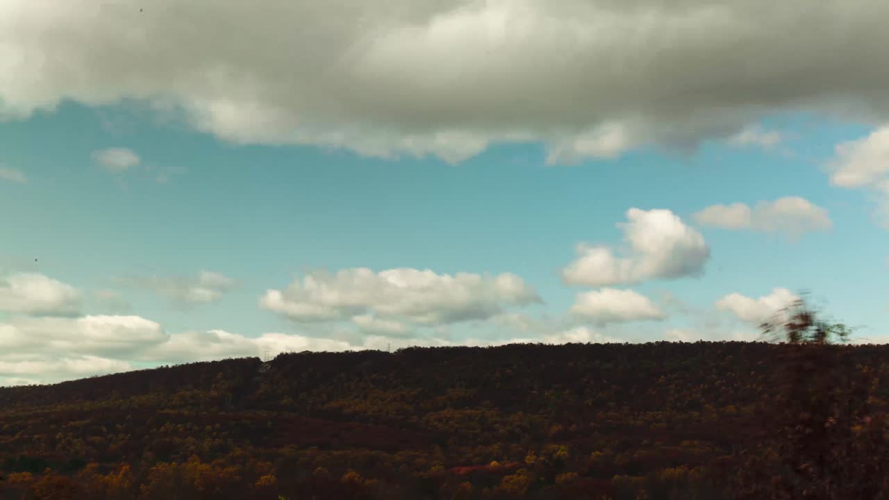 lapso de tiempo de las nubes moviéndose sobre una ladera cubierta de árboles en el otoño