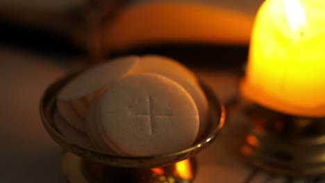 communion hosts in twilight illuminated by the light of a lit candle