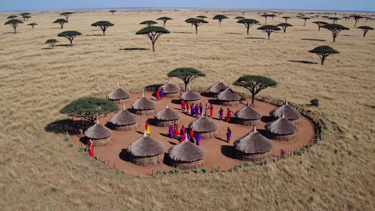 Aerial video captures a traditional village with thatched huts and people in colorful attire, set