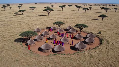 aerial video captures a traditional village with thatched huts and people in colorful attire, set