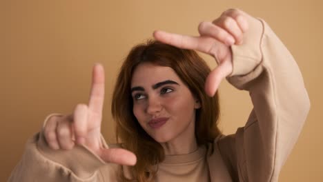 cheerful woman showing frame gesture with fingers in studio