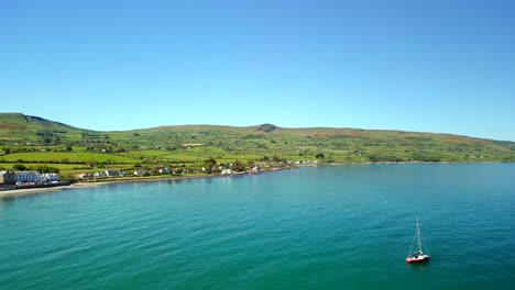 aerial video of the antrim coastal route on a bright and sunny day. the blue sea and green mountains can be seen. filmed in ballygally in 4k, 60fps and with rec800 color.