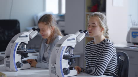 two young students use microscopes in a science laboratory