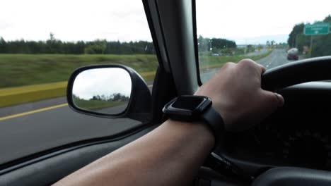 close-up hand on steering wheel driving on interstate highway